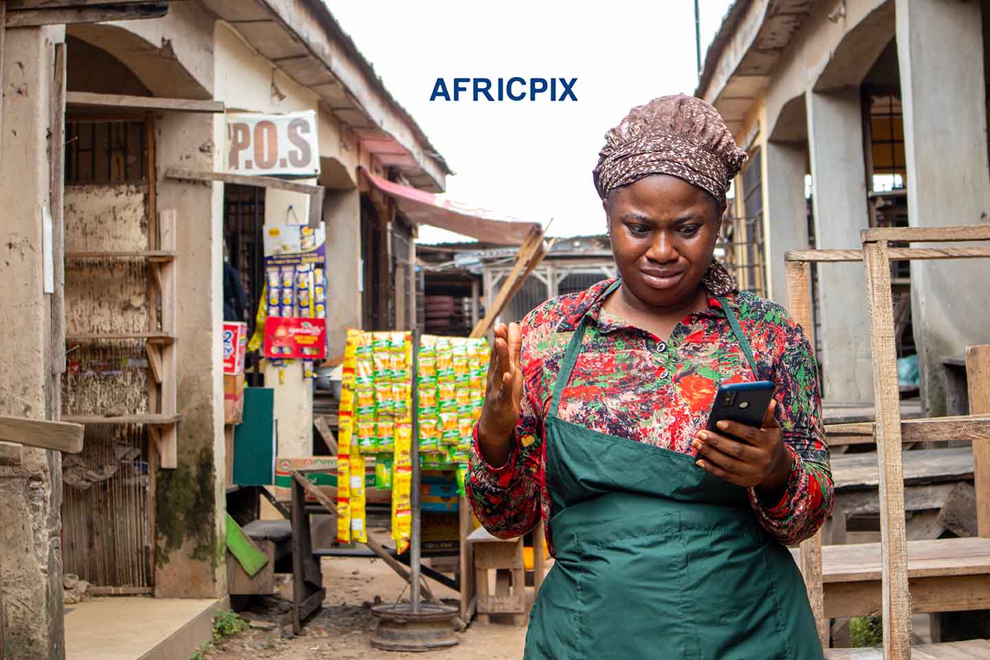 Surprised African Woman Holding Phone in Front of Her Shop